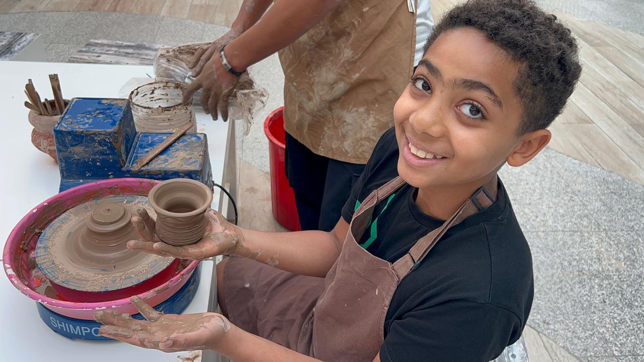 Sami shaping a clay pot on a pottery wheel